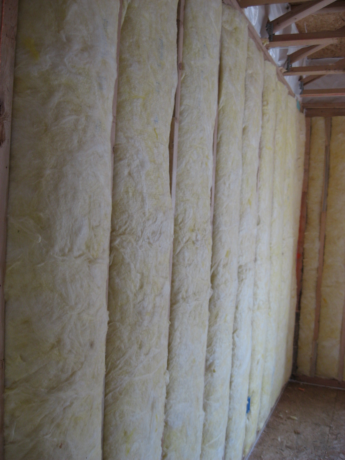 Unfaced fiberglass batt insulation is installed to completely fill the wall cavities 