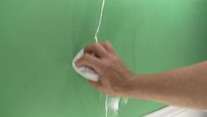 photo wiping off excess caulk from a plaster wall crack