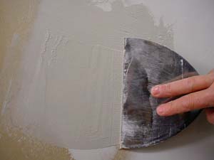 photo applying a second coat of joint compound over a patch