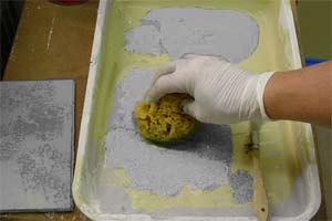 photo demonstrating how to load a sponge with painting glaze to apply a stone faux finish