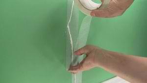 photo applying fiberglass mesh tape to a wall crack