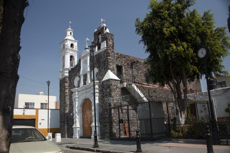 18th century white painted church in Mexico City between the two-color streets that adorn with the yellow-white facades that give. Adorn with the yellow-white royalty free stock image