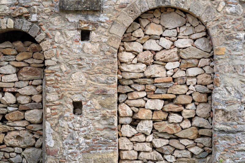 Ancient stone wall with an arch in a niche. Ancient stone and old wall with an arch in a niche closeup for a background or for wallpaper stock images