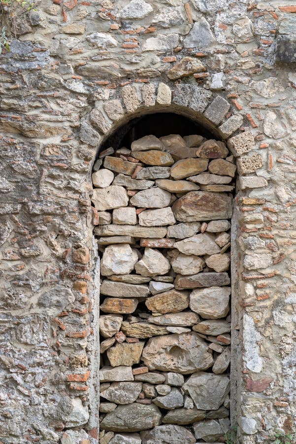 Ancient stone wall with an arch in a niche. Ancient stone and old wall with an arch in a niche closeup for a background or for wallpaper stock image
