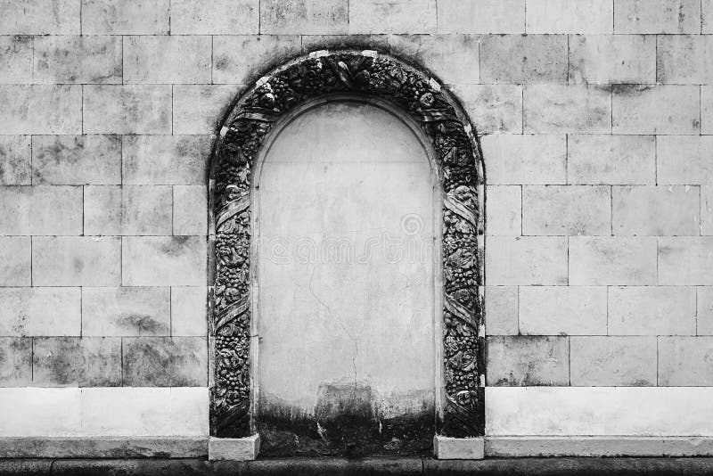 Antique stone wall with ornament arch in the middle. Antique old stone wall with ornament arch in the middle, grey facade background stock photography