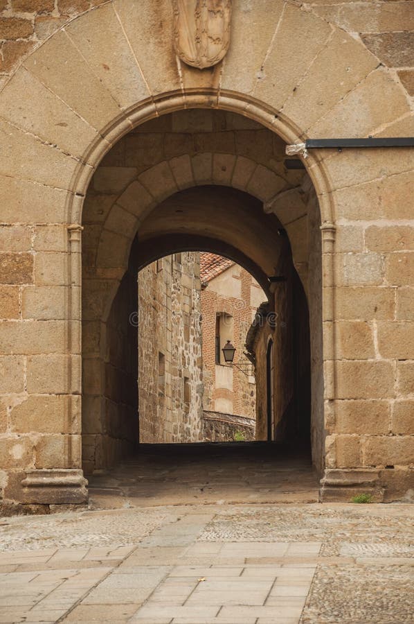 Arch gateway passing to an alley between gothic stone buildings in Plasencia. A cute, small countryside village, full of old buildings in western Spain royalty free stock image