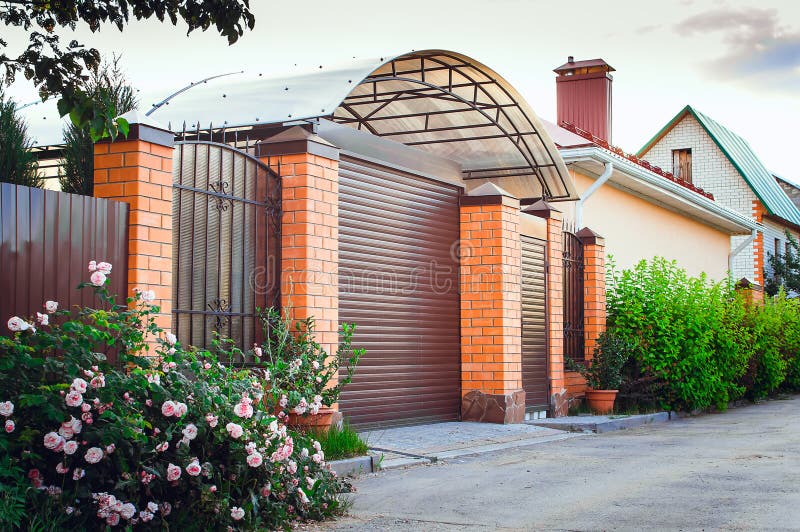 A brown fence made of polyprofile with a canopy in a modern style with brick columns, the design of a country house.  royalty free stock photo