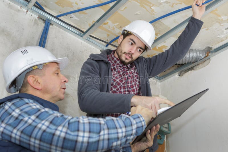 Builders fastens profile using cordless screwdriver. Roof royalty free stock image