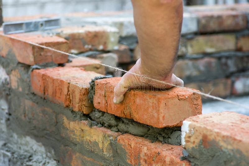 Building brick block wall on construction plant. Worker builds a brick wall in the house. Construction worker laying bricks on ext. Erior walls royalty free stock photography