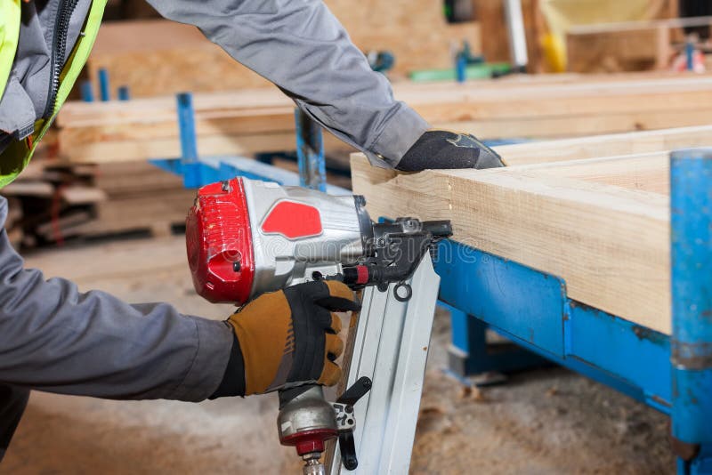 Building a wall for frame house.Worker use Framing Nailer to attach wooden beams. stock images