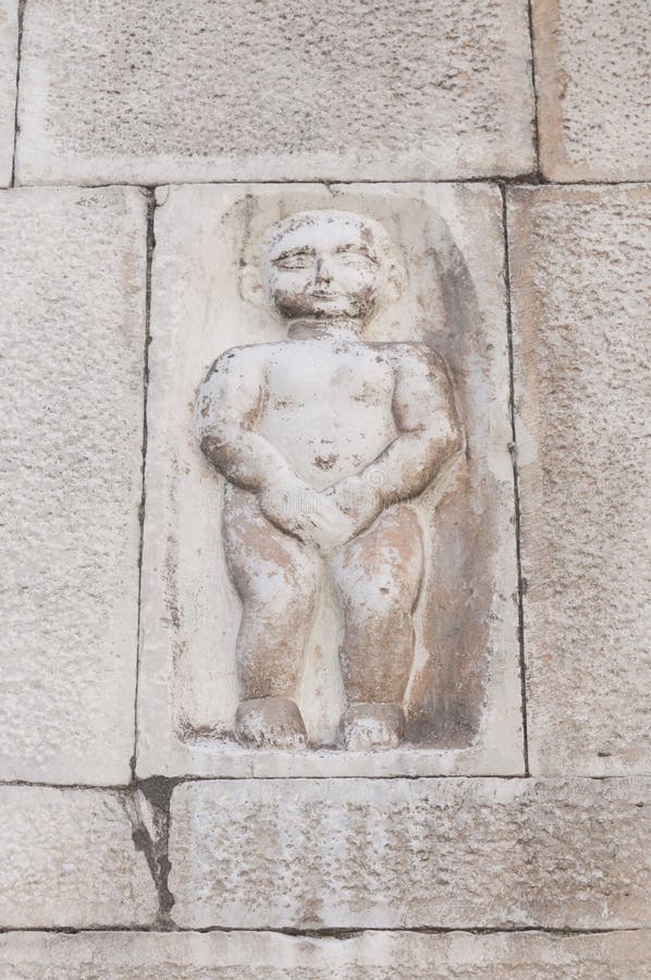 Carrara Italy: bas-relief depicting a puppet covering his private parts on the facade of a building in Duomo square royalty free stock photos