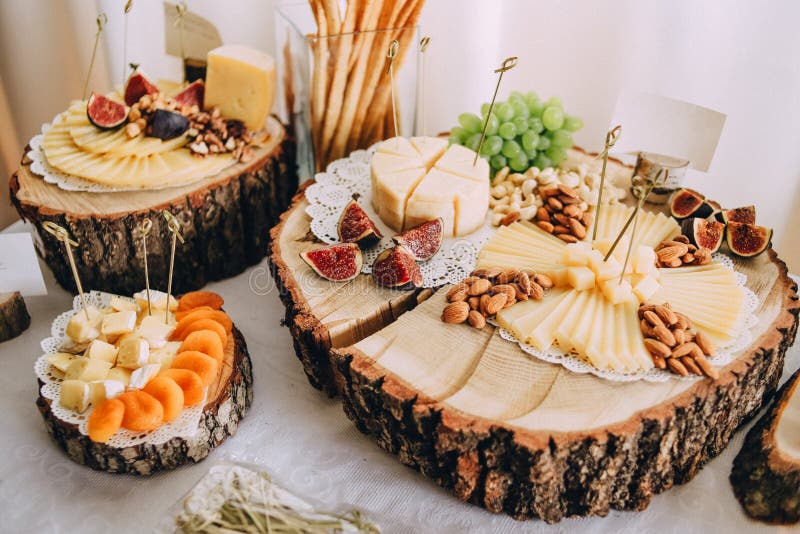 Cheese fruit snacks buffet table eco wooden coasters. Cheese and fruit snacks at the buffet table beautifully decorated on eco wooden coasters, delicious, food stock images