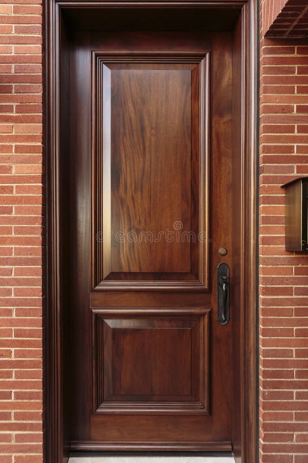 Closed Wooden Front Door of a Luxury Home. Closed wooden front door of an upscale home, with a black door handle, and framed by the brick house. Mailbox is also stock photos