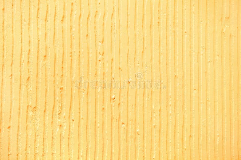 Textured yellow background with plaster vertical lines and stripes. Closeup of the wall with a decorative yellow colored plaster vertical lines and stripes royalty free stock image