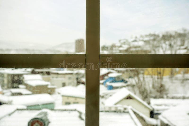 Closeup wooden frame of window and glass with blurry outside view of snow capped city royalty free stock photos