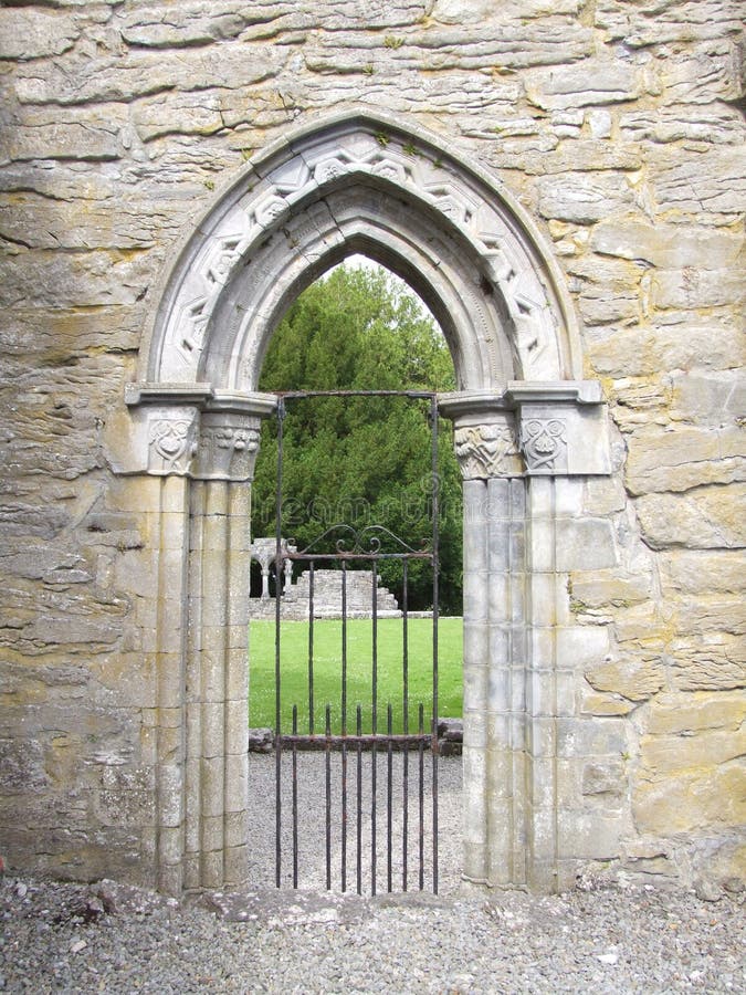 Decorative Stone Arch Gateway. A decorative stone archway with old rusted iron gate taken in Cong Abbey, Ireland royalty free stock photo