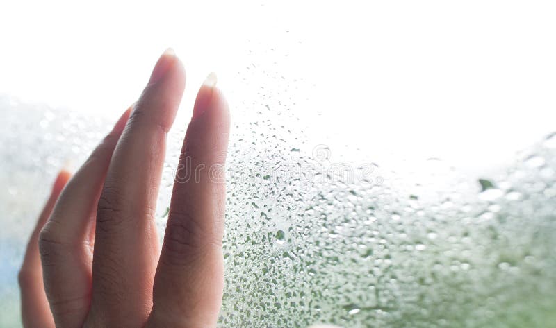 Fingers on the glass with water droplets. Hand young woman with fogged on the window. Drops of rain on glass background. Selective royalty free stock photo