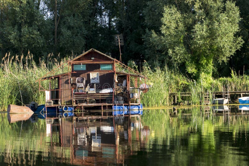 Floating house in the swamp. Pontons provide floating on the water. Old raft with neatly arranged details. The environment of lush vegetation of trees and stock image