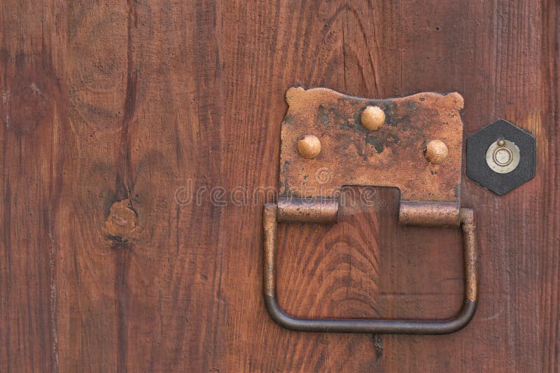 Forged metal door handle with a ring on a wooden door stock image
