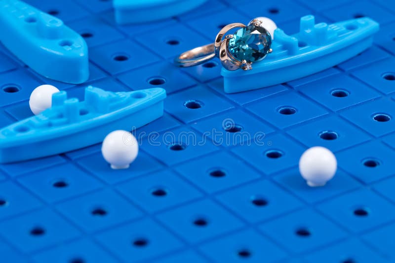 Gold ring lies on the game Board with toy military ships. A gold ring lies on the game Board with toy military ships ready for battle royalty free stock image