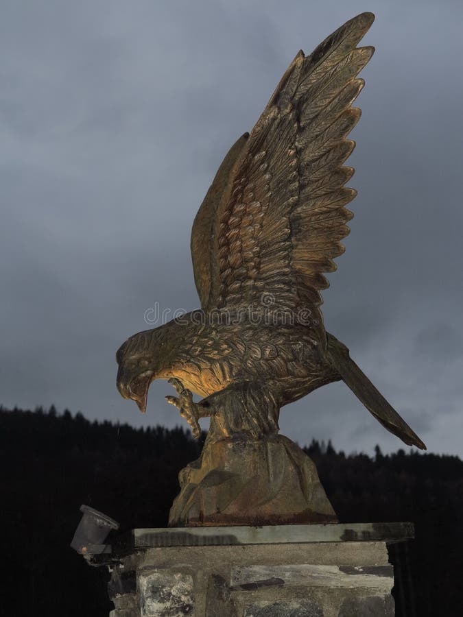 Golden eagle, model, statuette, on stone plinth, lit by spotlight at dusk. A bronze model of a golden eagle, perched on a stone plinth, lit by a low spotlight stock image