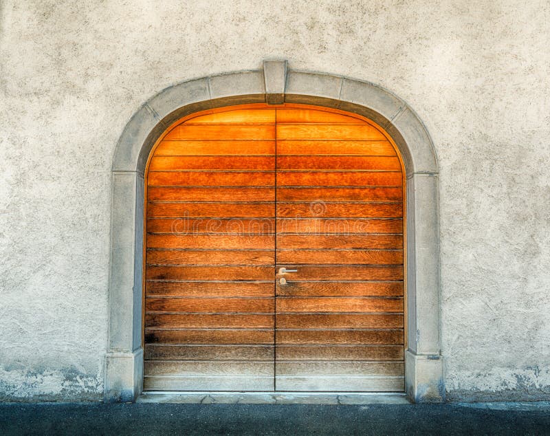 Massive winged wooden door in a stone wall with a granite door arch. Horizontal view of a massive winged wooden door in a stone wall with a granite door arch stock photos