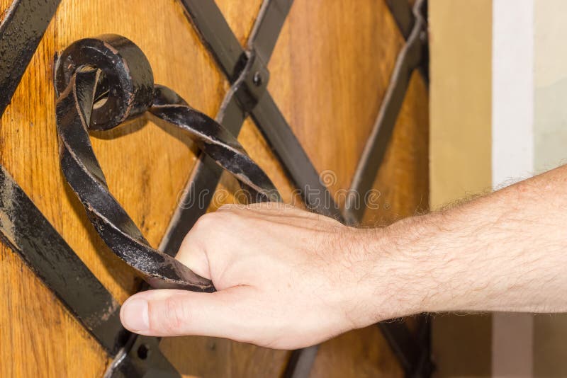 Human hand holds the iron door handle of monastery closeup royalty free stock photo