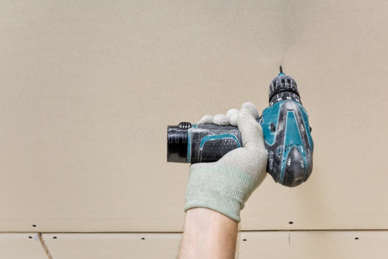 Installation of drywall. Worker`s hand with a screwdriver. Installation of drywall. A worker`s hand with a screwdriver is screwing a screw into plasterboard stock images