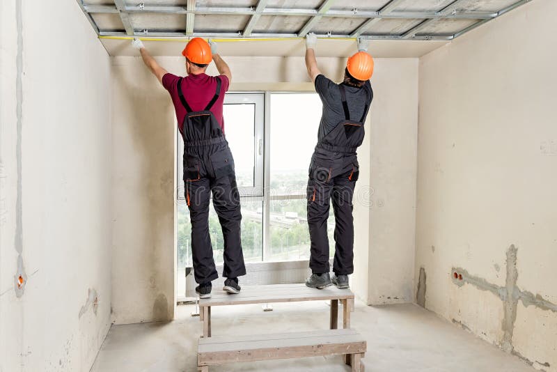 Installation of drywall. Workers are measuring. The ceiling royalty free stock photos