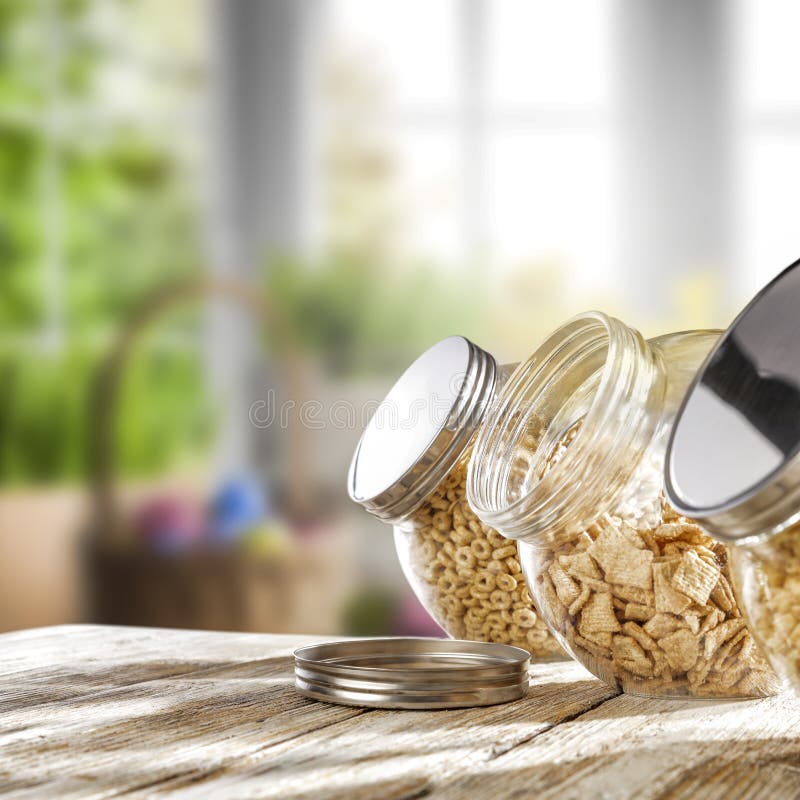 Kitchen interior with wooden table background and blurred view of sunny spring outside the window. Cereal in glass jars. stock photography