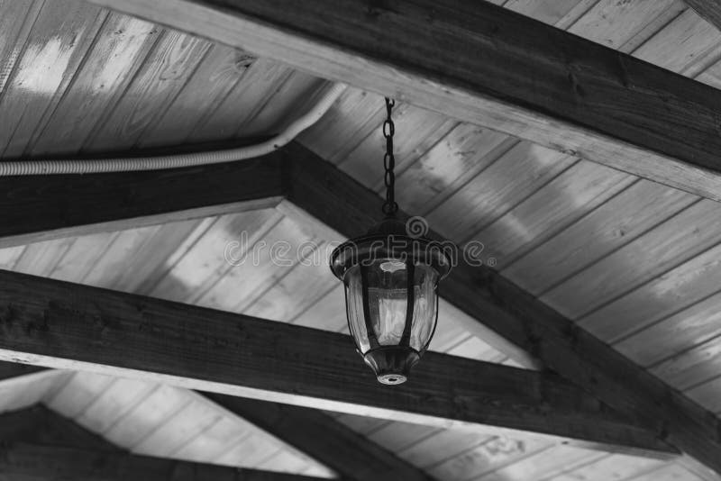 A lantern with iron fixtures to the wall and a glass canopy mounted on a wooden house. A lantern with iron fixtures to the wall and a glass canopy mounted on a royalty free stock photo