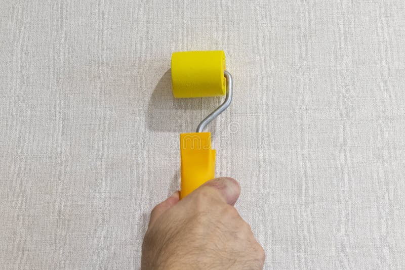 Man is sealing down wallpaper seam with a rubber roller. Man is sealing down wallpaper seam with a rubber roller royalty free stock images