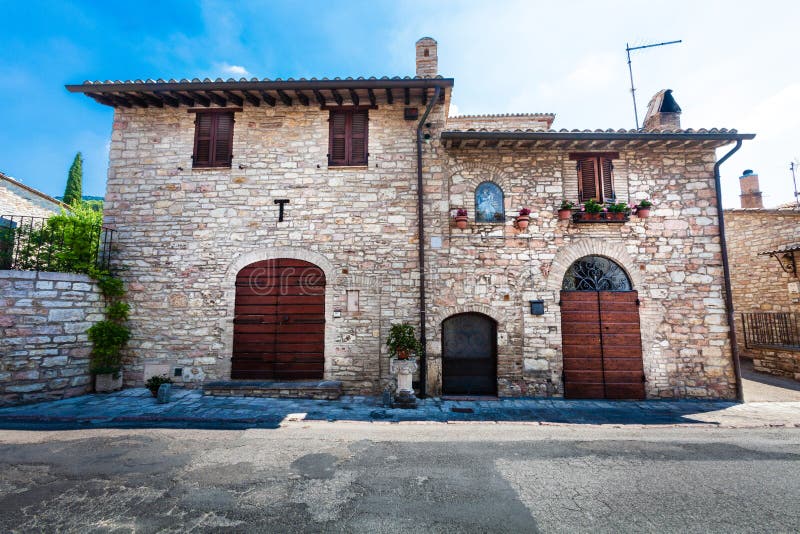 Mediterranean rustic house. Brick building, external facade. Entrance with ancient wooden doors. Location: Assisi, Italy. Blue sky stock images