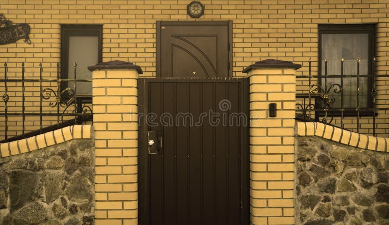Metal gates modern yellow brick cottage stock image
