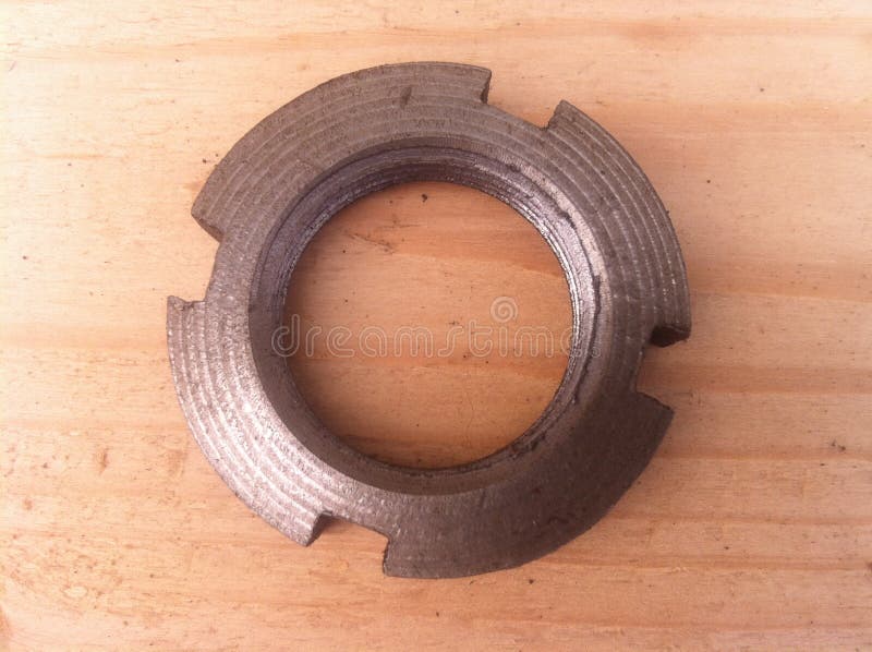 Metal product slotted nut for fastening. Metal product clean slotted nut for fastening shot on a light wooden surface with real natural close-up shot royalty free stock images