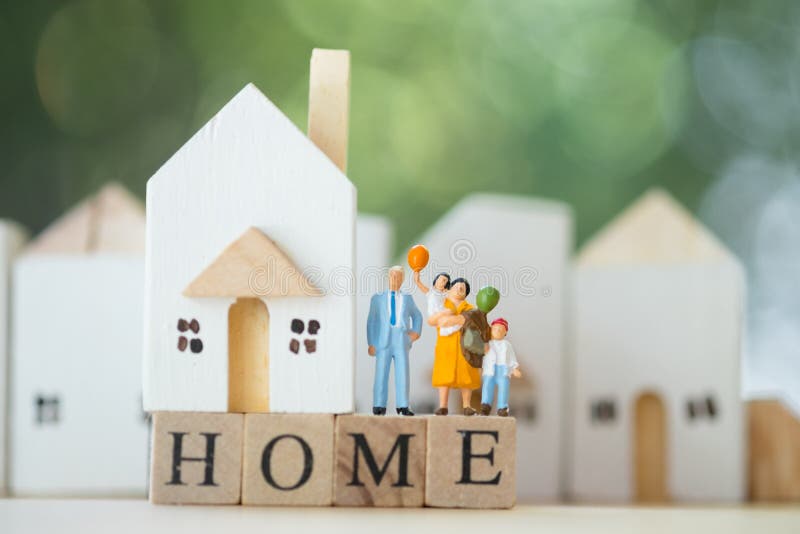 Miniature people: Family stand on wood block words HOME and house background. The concept of family values. Family continuation and family planning. Caring for stock images