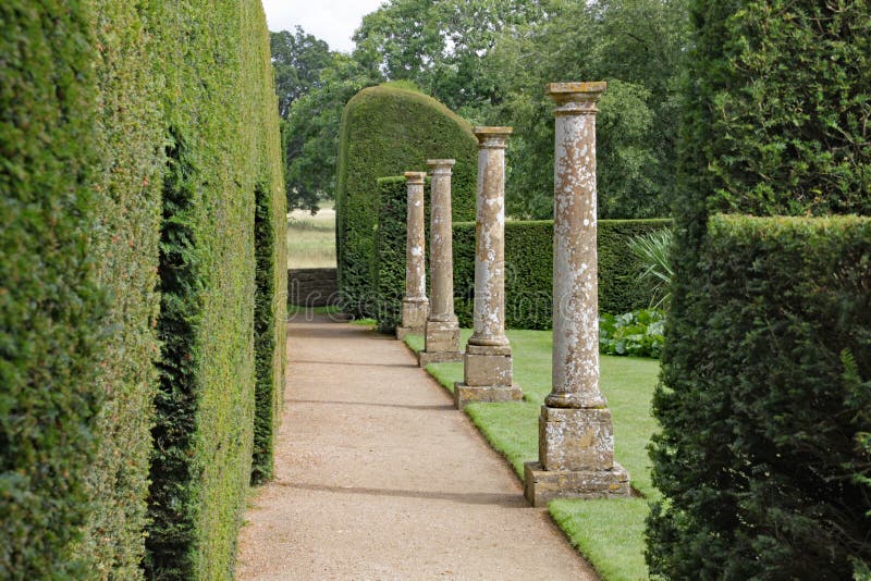 Old stone columns stand by a hedge with arch shaped doorways cut in it at an English country house in Somerset, UK. royalty free stock image Old stone columns stand by a hedge with arch shaped doorways cut in it at an English country house in Somerset, UK. royalty free stock image