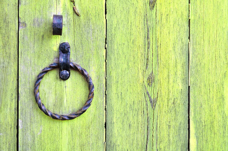 Old textured yellow wooden door with aged metal door handle in the form of ring. royalty free stock photography
