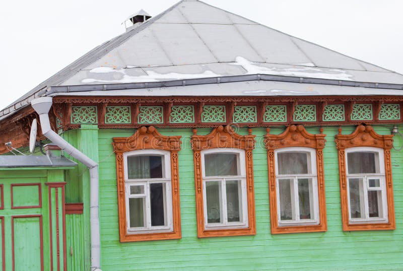 Old wooden house of green color with beautiful brown platbands on the windows stock image