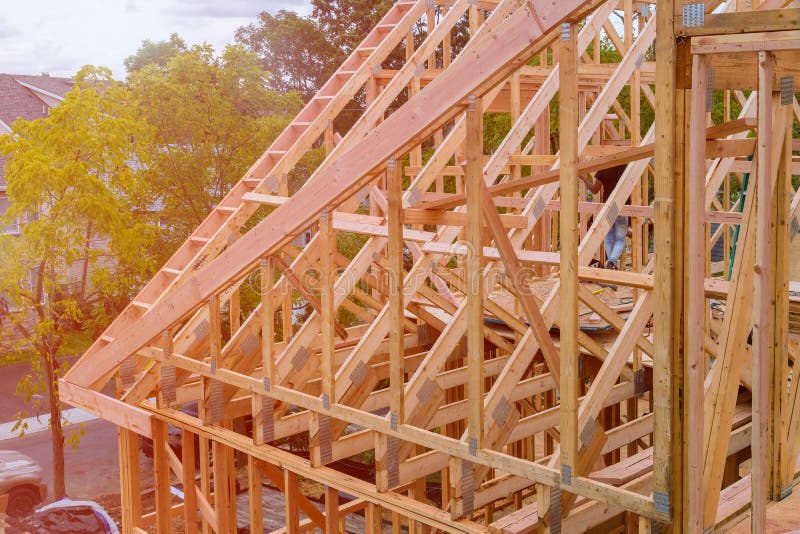 Panorama of condominium building with under construction wooden house with timber framing, truss, joist, beam close-up royalty free stock photo