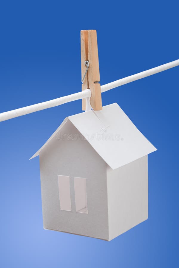 Paper house on washing line. Paper house hung on clothes or washing line with blue background stock image