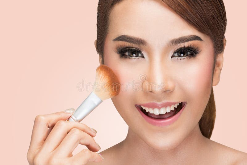 Portrait of a asian woman applying dry cosmetic tonal foundation on the face using makeup brush royalty free stock photos