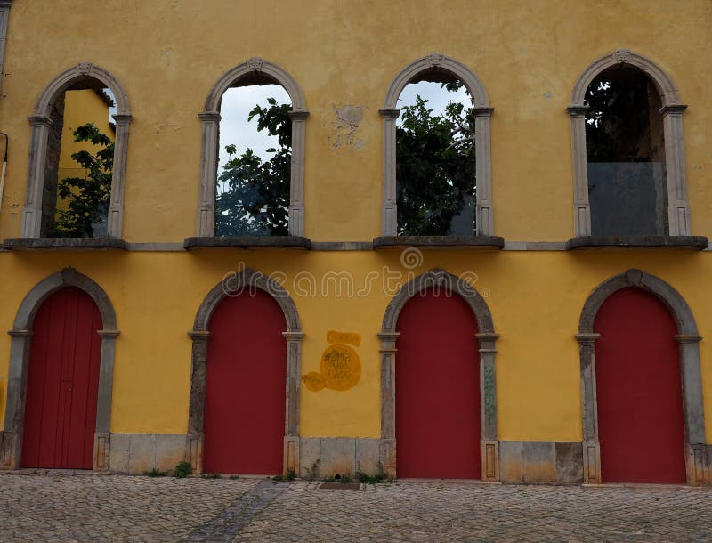 Red Doors And Yellow Walls In Tavira Portugal. Building with brightly painted red doors set in arched doorways in a yellow building in Tavira Portugal stock photos Red Doors And Yellow Walls In Tavira Portugal. Building with brightly painted red doors set in arched doorways in a yellow building in Tavira Portugal stock photos