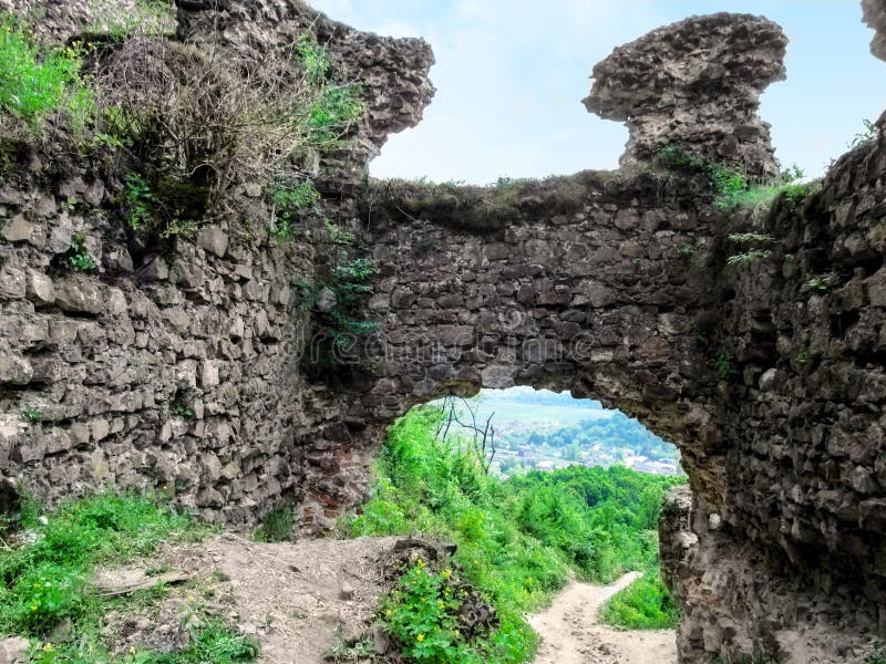 The remains of the gates of the ancient Khust fortress. The passage between the ruins of medieval stone walls covered with plants stock image