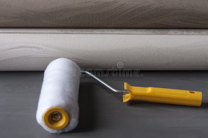 Rolls of wallpaper and roller for their sticking. The concept of tools for home repair and interior renovation indoors. Copy space royalty free stock photography