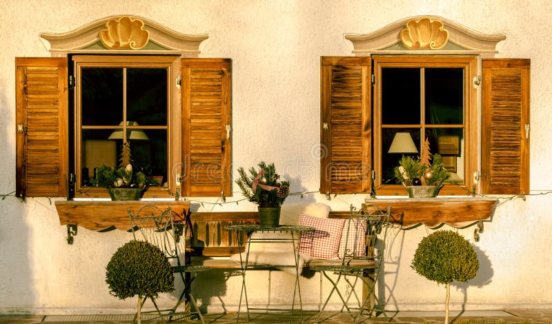 Rustic house facade. With two wooden windows and shutters, a garden table with its chairs and Christmas decorations stock image