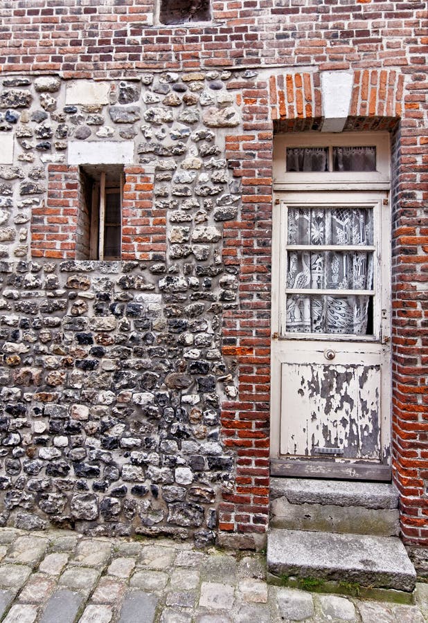 Rustic house facade with white exterior doors in Honfleur, France. Red brick rustic house building facade with old white exterior wooden doors in Honfleur stock images