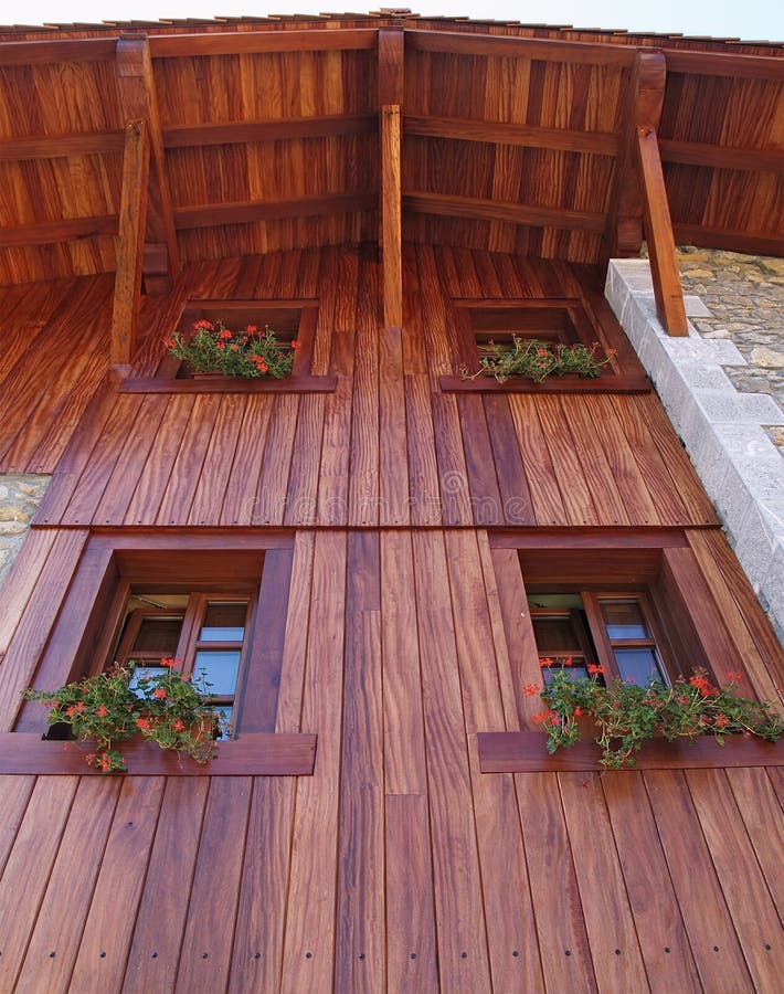 Rustic house with wood facade. Nad flowers in the windows stock photos