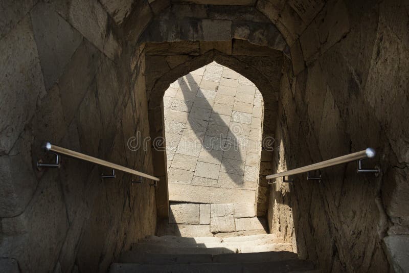 Shadow in the arch doorway, railing, stairs down the entrance through the arch. Shadow in the arch doorway, staircase leading down through the arch, stairs steps royalty free stock photo