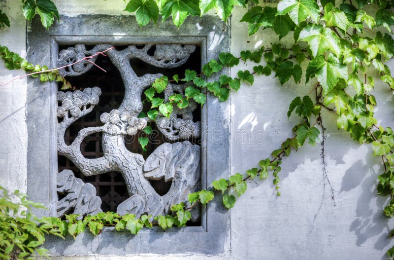 Stone carving of a tree as decoration for a window in a wall in China royalty free stock photos